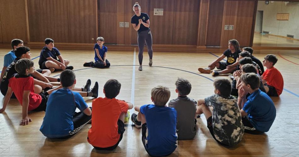 Selbstverteidigungs-Workshop. Kinder sitzen im Kreis. Vortragende instruiert.